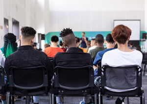 Menschen verschiedener Hautfarbe sitzen in einem Klassenraum