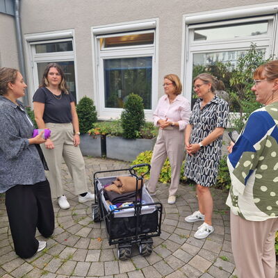 5 Frauen stehen um einen Bollerwagen