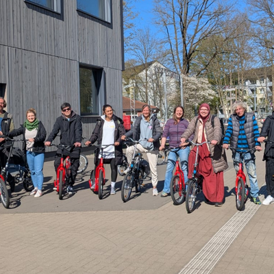 eine Gruppe von Menschen auf Rollern und Fahrrädern in einer Reihe,