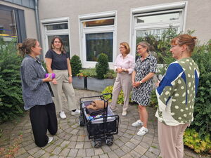 5 Frauen stehen um einen Bollerwagen
