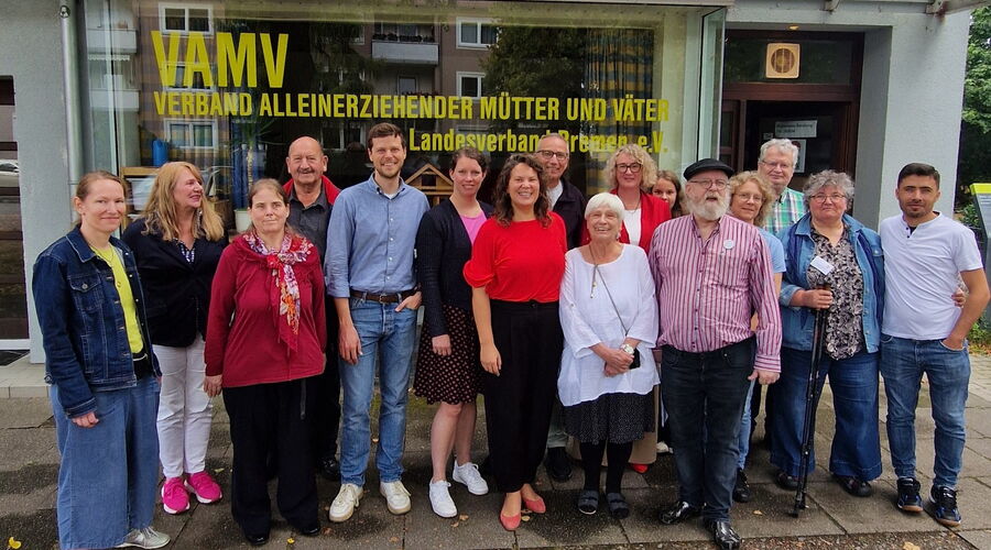 Gruppenfoto mit vielen Menschen vor dem Gebäude mit Schriftzug VAMV Verband alleinerziehender Mütter und Väter
