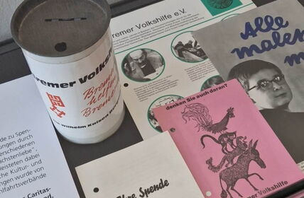Ausstellungsstücke: Alte Spendendose, alte Schriften und Flyer