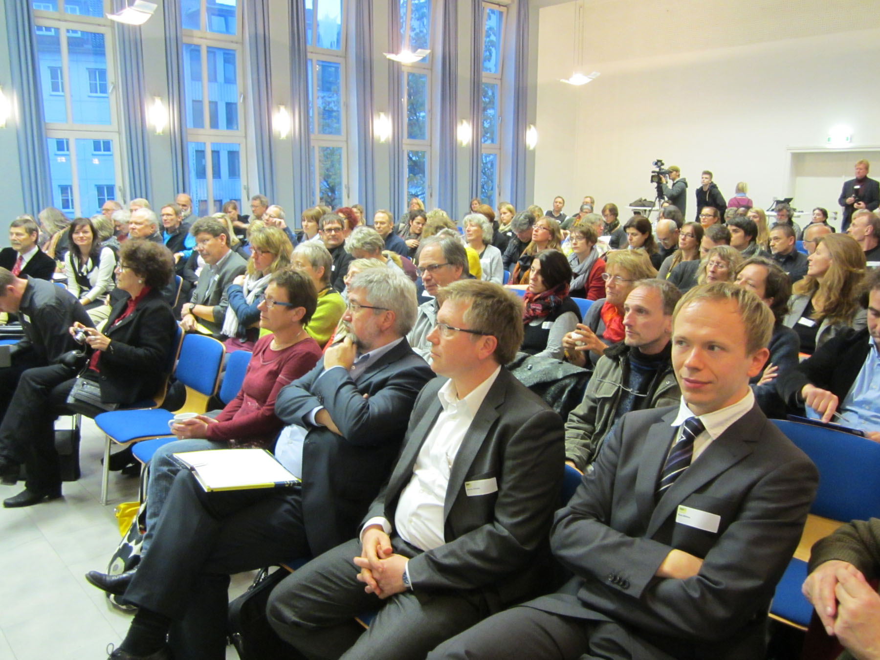 Saal mit vielen Menschen in Stuhlreihen