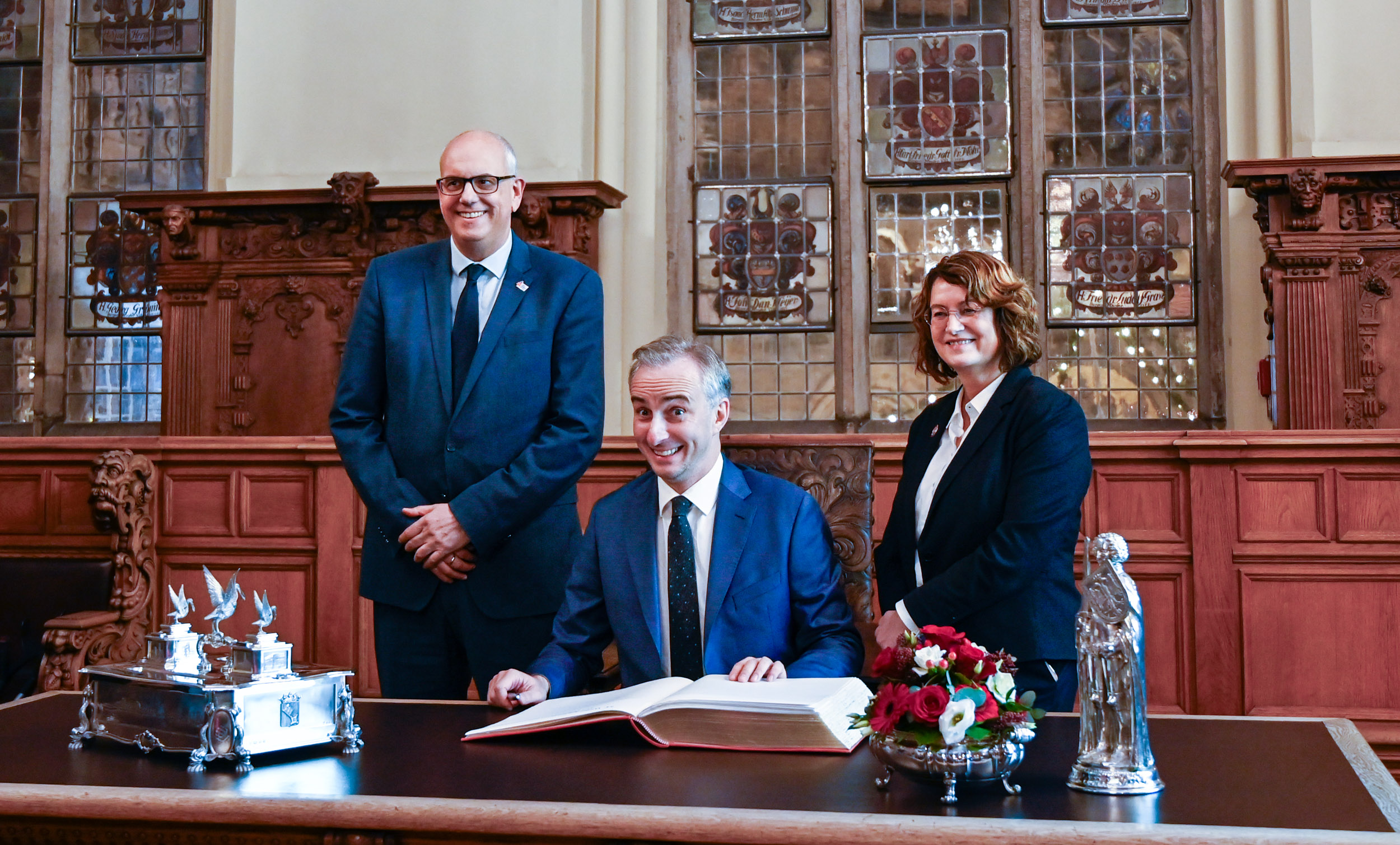 Festlicher Schreibtisch im Bremer Rathaus, ein Mann sitzt, zwei Personen stehen links und rechts daneben